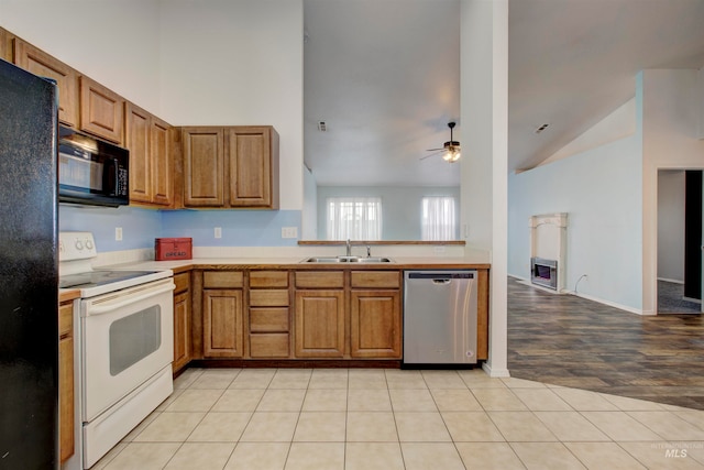 kitchen featuring ceiling fan, sink, black appliances, light hardwood / wood-style flooring, and lofted ceiling