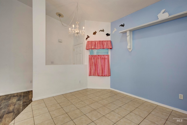 spare room featuring a notable chandelier and light hardwood / wood-style flooring