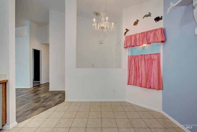 spare room with a notable chandelier, high vaulted ceiling, and light hardwood / wood-style flooring