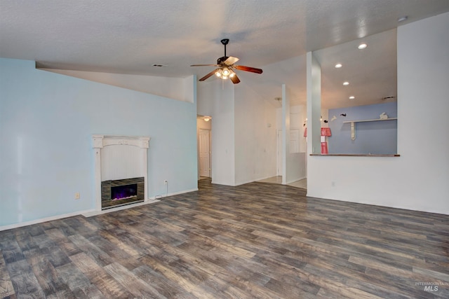 unfurnished living room featuring lofted ceiling, dark wood-type flooring, a stone fireplace, ceiling fan, and a textured ceiling