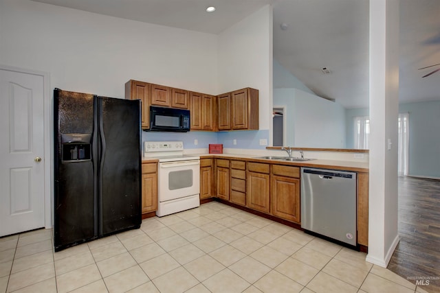 kitchen featuring ceiling fan, sink, a high ceiling, light hardwood / wood-style floors, and black appliances