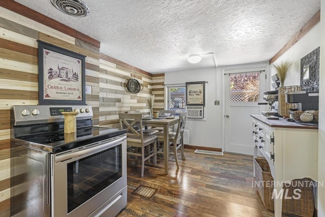 kitchen featuring cooling unit, a textured ceiling, wood walls, dark wood-style flooring, and electric stove