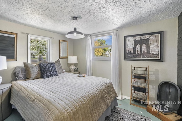 bedroom featuring baseboards, multiple windows, and a textured ceiling
