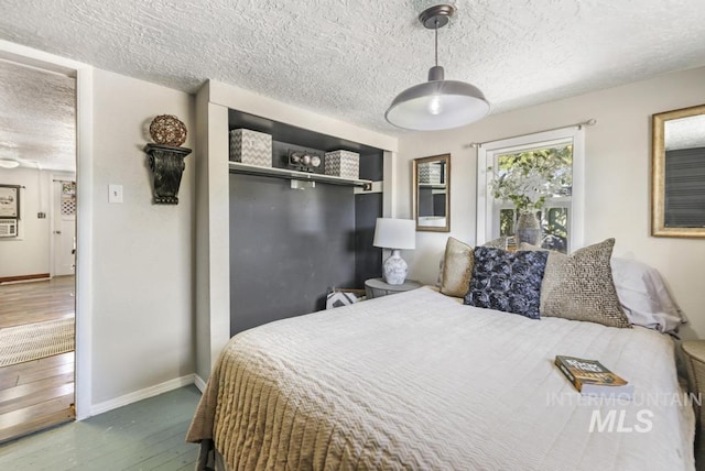 bedroom featuring baseboards, hardwood / wood-style flooring, a textured ceiling, and a closet