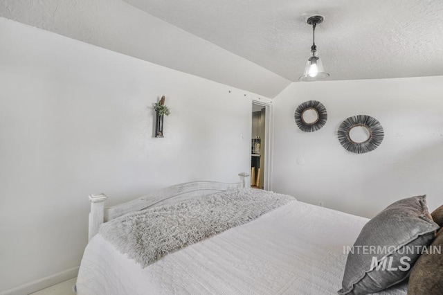 bedroom with a textured ceiling, baseboards, and vaulted ceiling