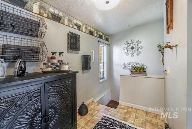 interior space with a textured ceiling and baseboards