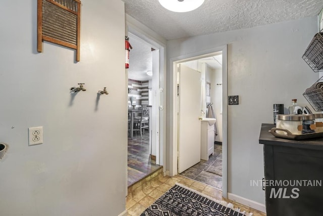 hall with baseboards and a textured ceiling