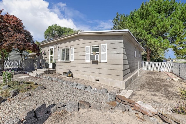 view of side of home with crawl space and fence