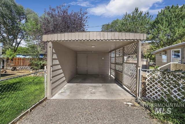 view of vehicle parking with a carport, fence, and driveway