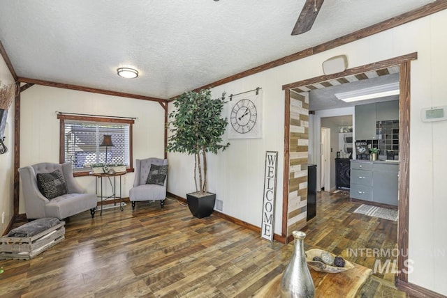 sitting room featuring ornamental molding, a ceiling fan, hardwood / wood-style flooring, and a textured ceiling