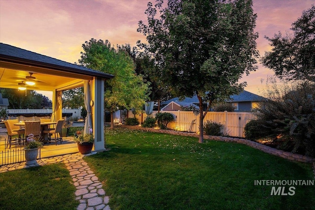 yard at dusk with a patio area and ceiling fan