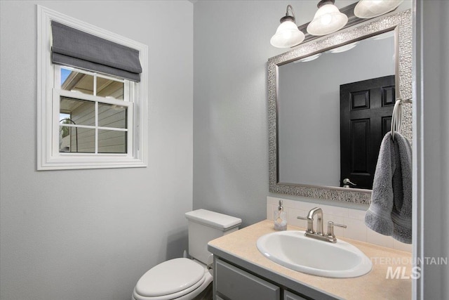 bathroom with backsplash, vanity, and toilet