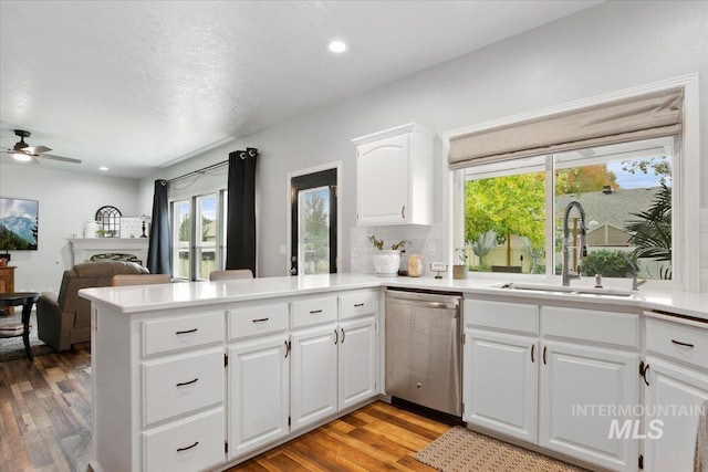 kitchen with sink, light wood-type flooring, dishwasher, kitchen peninsula, and white cabinets