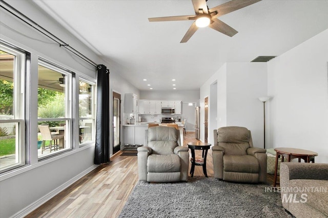 living room with light hardwood / wood-style floors and ceiling fan