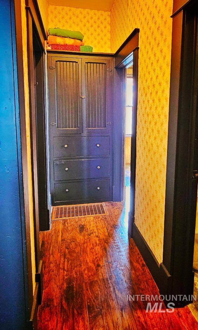 hallway with wallpapered walls, baseboards, and dark wood-style flooring