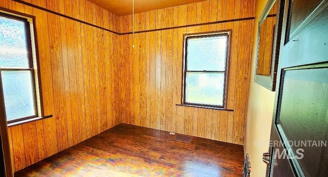 unfurnished room with visible vents and wood walls