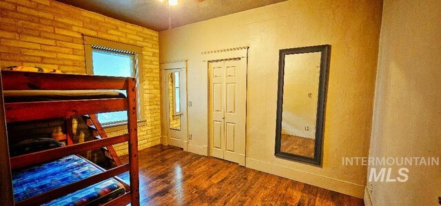 bedroom featuring brick wall and wood finished floors