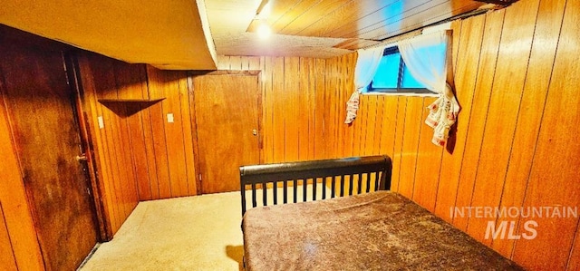 carpeted bedroom featuring wood walls