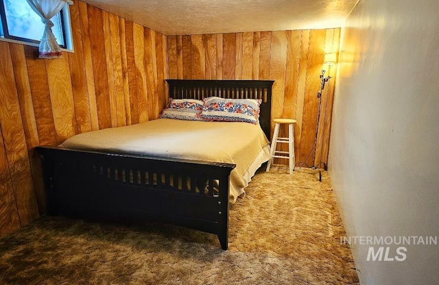 bedroom featuring a textured ceiling, wood walls, and carpet flooring