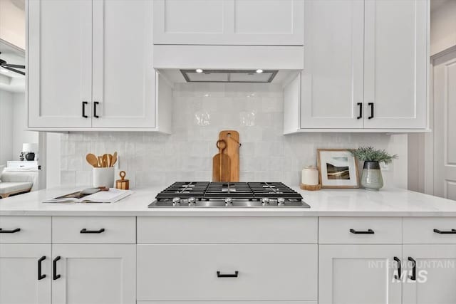 kitchen featuring light stone countertops, tasteful backsplash, white cabinetry, and stainless steel gas cooktop