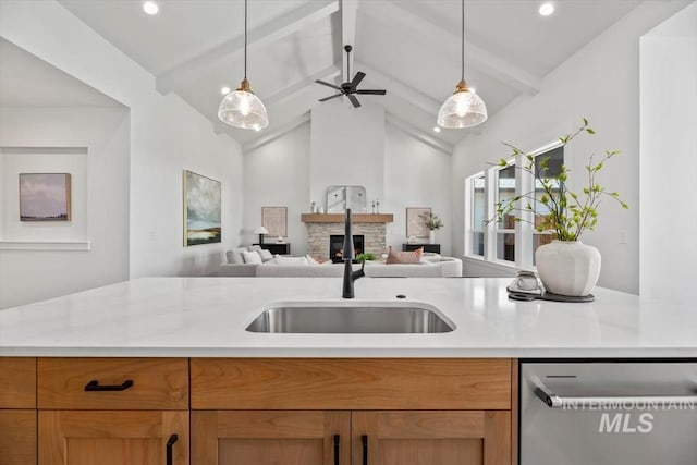 kitchen with sink, beam ceiling, dishwasher, a stone fireplace, and hanging light fixtures