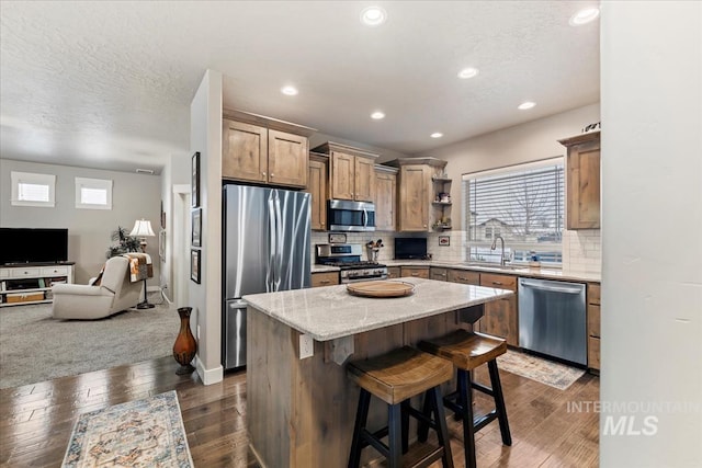 kitchen with a kitchen island, stainless steel appliances, dark hardwood / wood-style floors, tasteful backsplash, and a kitchen bar