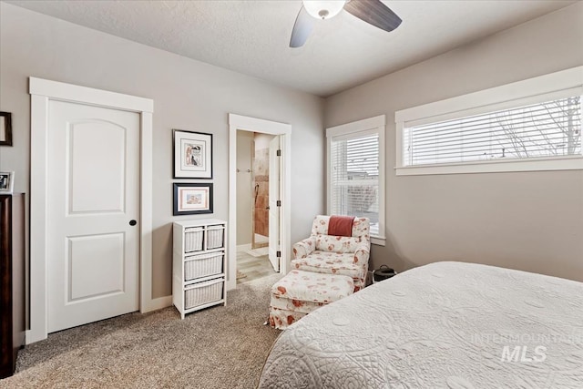 bedroom with ceiling fan, light colored carpet, ensuite bath, and a textured ceiling