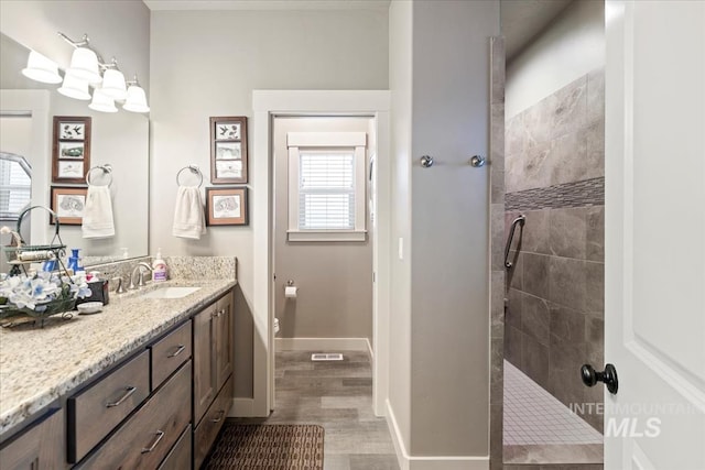 bathroom featuring tiled shower, vanity, and hardwood / wood-style floors