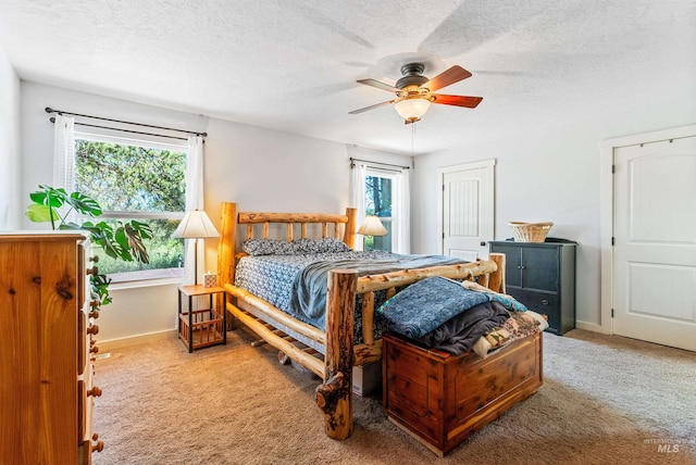 carpeted bedroom featuring multiple windows, ceiling fan, and a textured ceiling