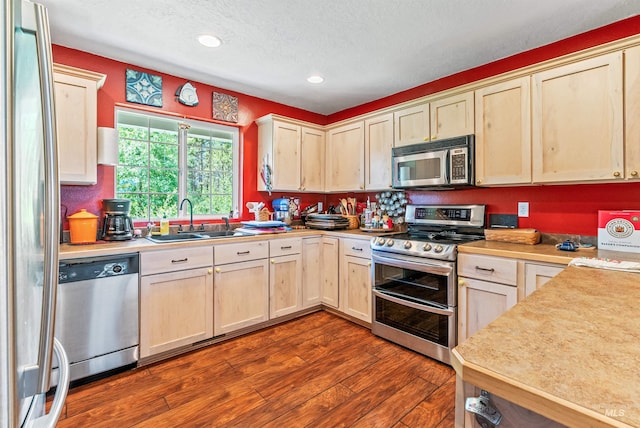 kitchen with hardwood / wood-style flooring, sink, stainless steel appliances, and a textured ceiling