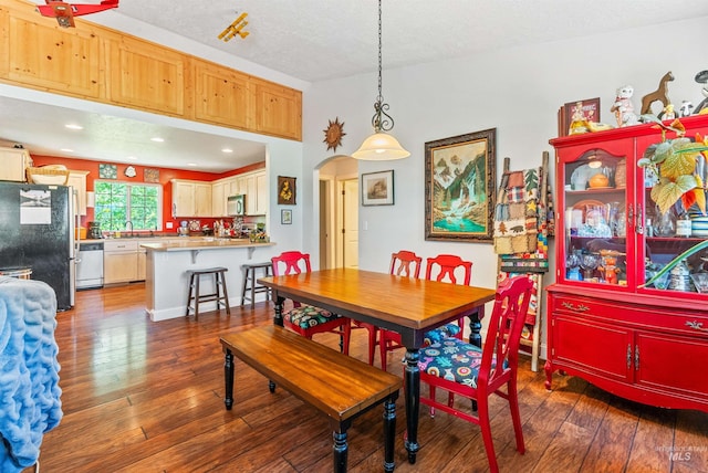 dining space featuring a textured ceiling, sink, and dark wood-type flooring