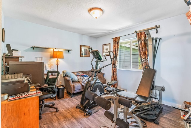 exercise room with hardwood / wood-style floors and a textured ceiling