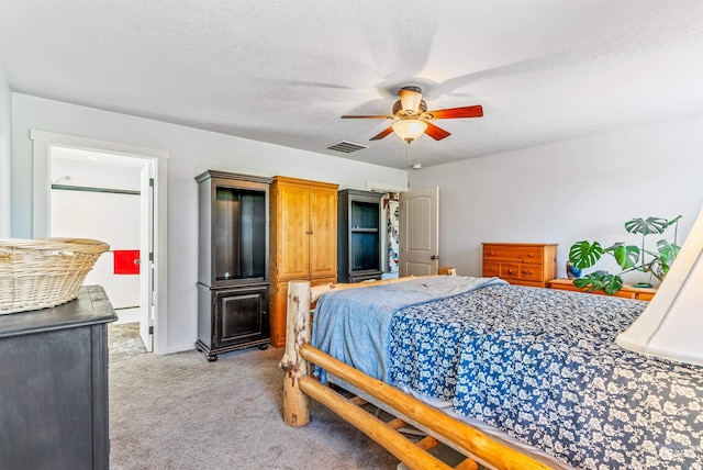 bedroom featuring light carpet, a textured ceiling, and ceiling fan