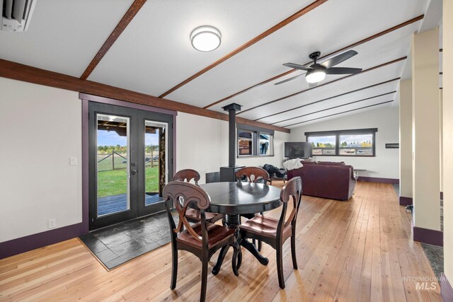 dining room with a wood stove, hardwood / wood-style flooring, ceiling fan, and baseboards