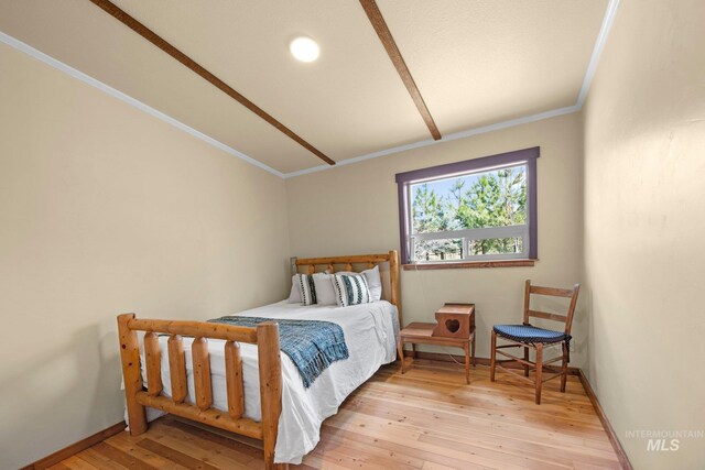 bedroom with light wood-style floors, ornamental molding, and baseboards