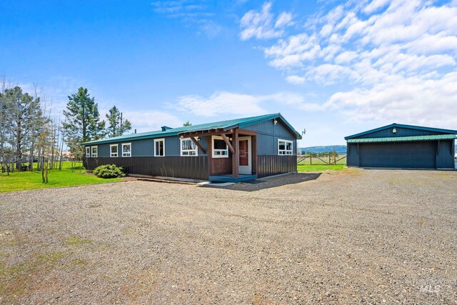 single story home with a detached garage, driveway, and an outbuilding