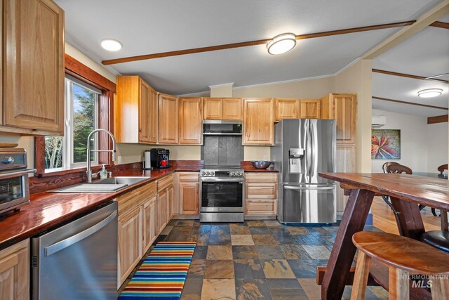 kitchen with stainless steel appliances, lofted ceiling, a sink, dark stone finish flooring, and butcher block countertops