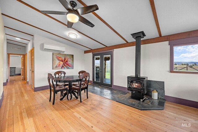 dining area with a wall mounted air conditioner, a wood stove, baseboards, ceiling fan, and hardwood / wood-style floors