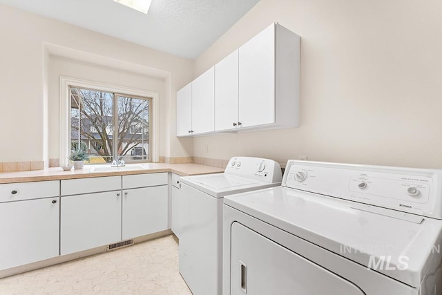 laundry room featuring cabinets, separate washer and dryer, sink, and a textured ceiling