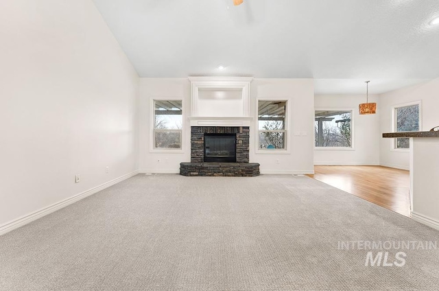 unfurnished living room with a stone fireplace and light colored carpet