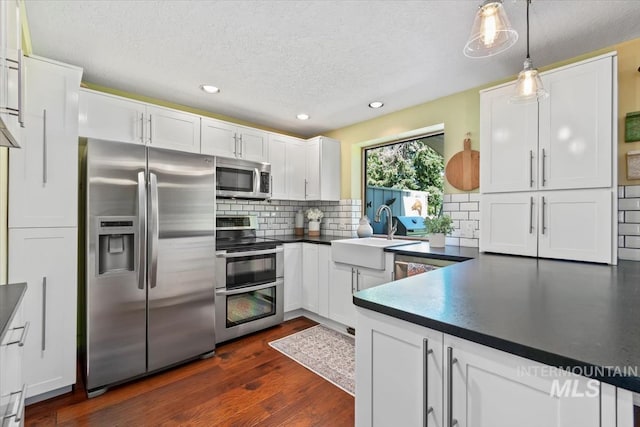 3001 S Roosevelt St Unit 9, Boise, ID 83705 - kitchen featuring appliances with stainless steel finishes, dark countertops, a sink, white cabinetry, and a textured ceiling