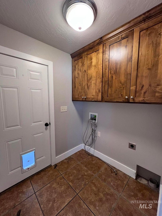 322 Linden Ave, Twin Falls, ID 83301 - laundry area featuring cabinet space, dark tile patterned flooring, baseboards, electric dryer hookup, and a textured ceiling