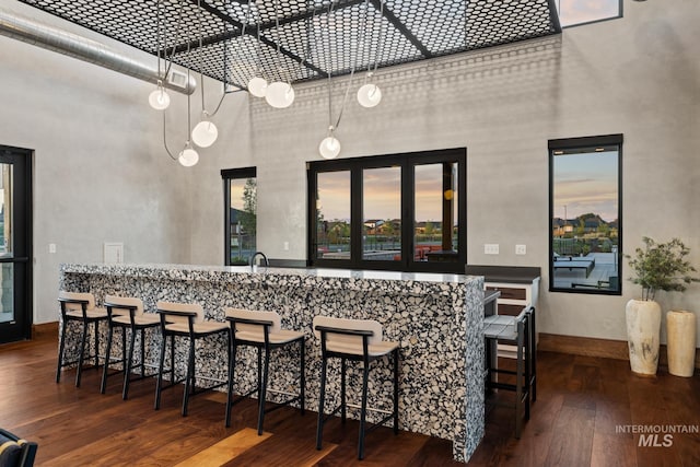 bar with a high ceiling and dark hardwood / wood-style floors