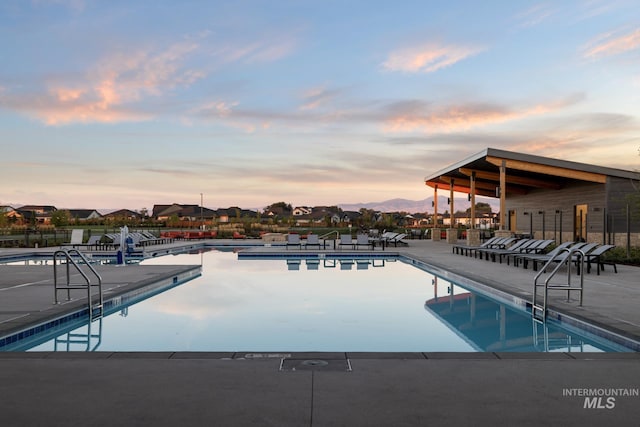 pool at dusk featuring a patio area