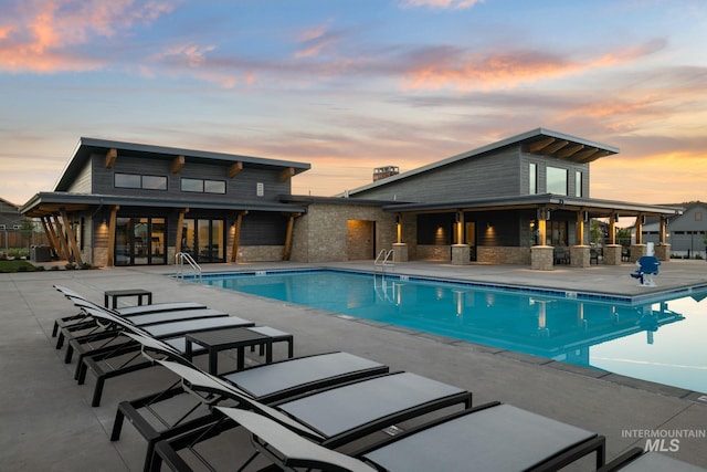 pool at dusk featuring a patio