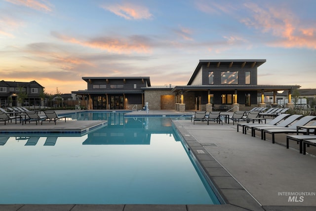 pool at dusk featuring a patio area