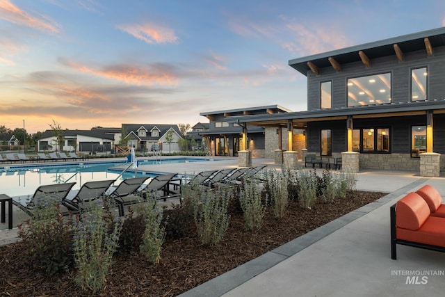 pool at dusk featuring a patio area