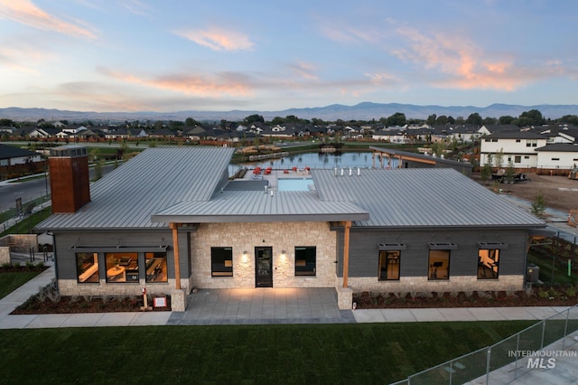 back house at dusk with a water and mountain view