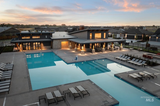 pool at dusk with a patio area