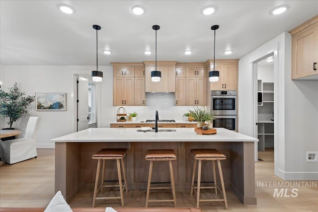 kitchen with light hardwood / wood-style flooring, light brown cabinets, and stainless steel double oven